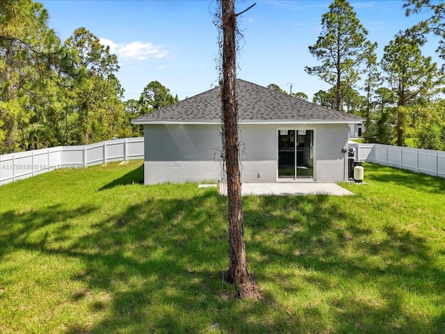 924 Berg St E, Lehigh Acres, FL 33974 - back of house with a yard, stucco siding, a fenced backyard, and roof with shingles