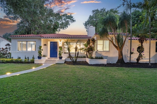 558 NE 94th St, Miami Shores, FL 33138 - view of front facade featuring a chimney, a yard, a tiled roof, and stucco siding