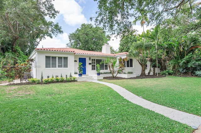558 NE 94th St, Miami Shores, FL 33138 - view of front of property featuring a front lawn, a tile roof, a chimney, and stucco siding