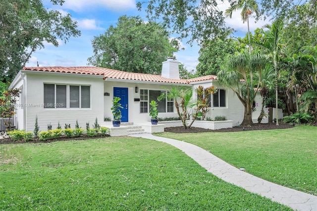 558 NE 94th St, Miami Shores, FL 33138 - view of front of home with a tile roof, a front lawn, a chimney, and stucco siding