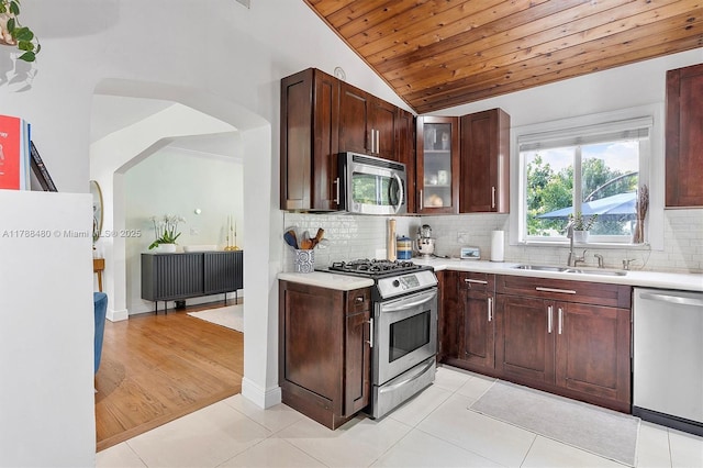 558 NE 94th St, Miami Shores, FL 33138 - kitchen with lofted ceiling, light countertops, a sink, arched walkways, and appliances with stainless steel finishes