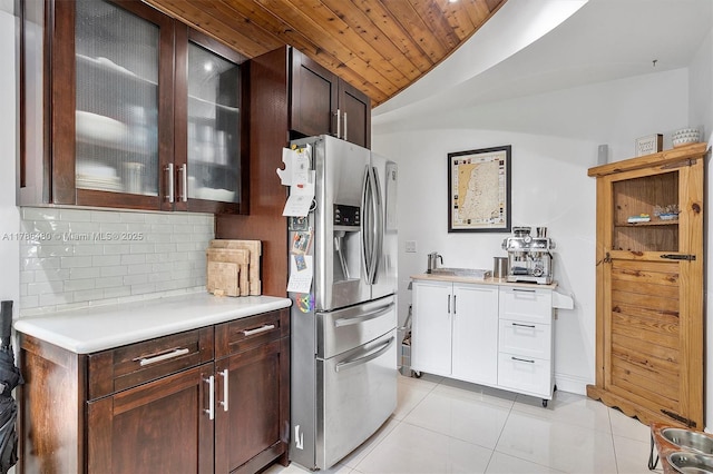 558 NE 94th St, Miami Shores, FL 33138 - kitchen featuring light countertops, backsplash, dark brown cabinets, light tile patterned floors, and stainless steel fridge