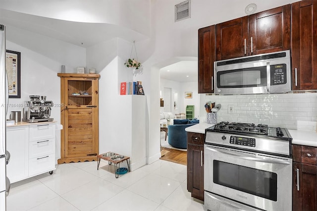 558 NE 94th St, Miami Shores, FL 33138 - kitchen with arched walkways, visible vents, decorative backsplash, light countertops, and appliances with stainless steel finishes