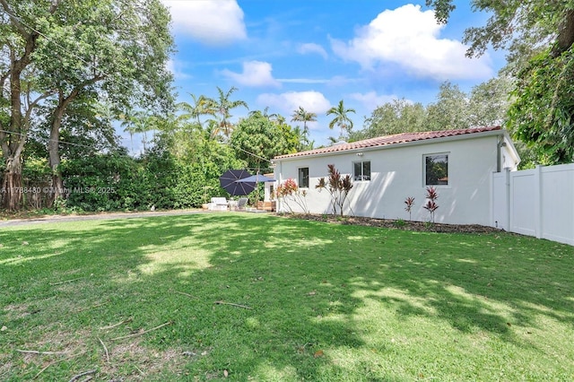 558 NE 94th St, Miami Shores, FL 33138 - rear view of property featuring a lawn, fence, a tiled roof, and stucco siding