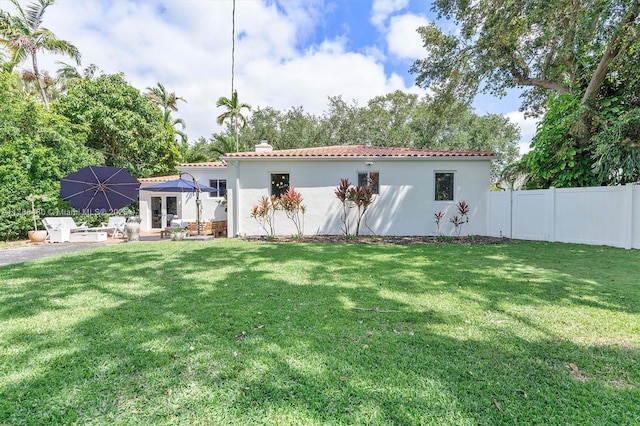 558 NE 94th St, Miami Shores, FL 33138 - rear view of house featuring stucco siding, a yard, a tile roof, and fence