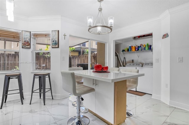 7225 NW 173rd Dr Unit 904-9, Hialeah, FL 33015 - kitchen with washing machine and clothes dryer, a breakfast bar area, marble finish floor, an inviting chandelier, and baseboards