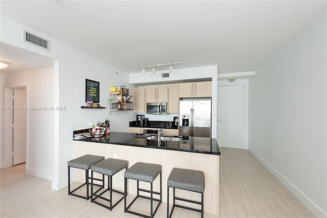 79 SW 12th St Unit 2011-S, Miami, FL 33130 - kitchen with visible vents, light brown cabinetry, a breakfast bar area, a sink, and appliances with stainless steel finishes