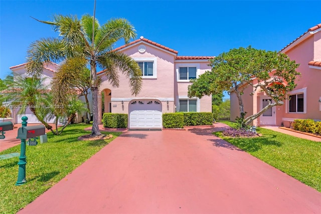 mediterranean / spanish house with a front lawn, driveway, a tiled roof, an attached garage, and stucco siding