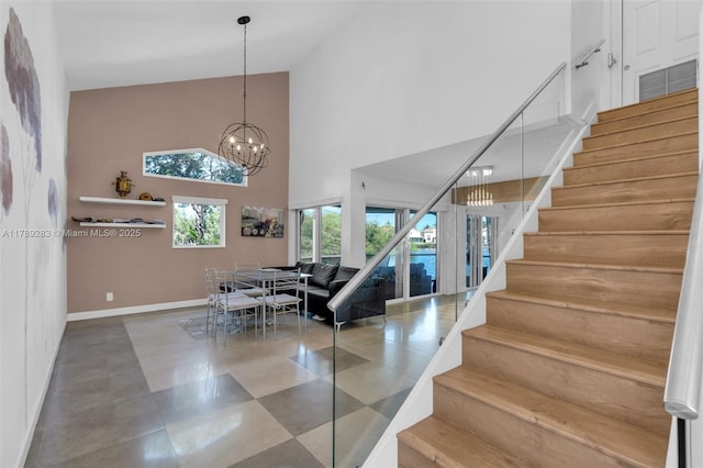 stairs with high vaulted ceiling, baseboards, and a notable chandelier