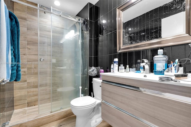 full bathroom with a shower stall, toilet, vanity, and tile walls
