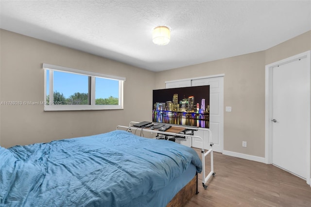bedroom featuring wood finished floors, a textured ceiling, and baseboards