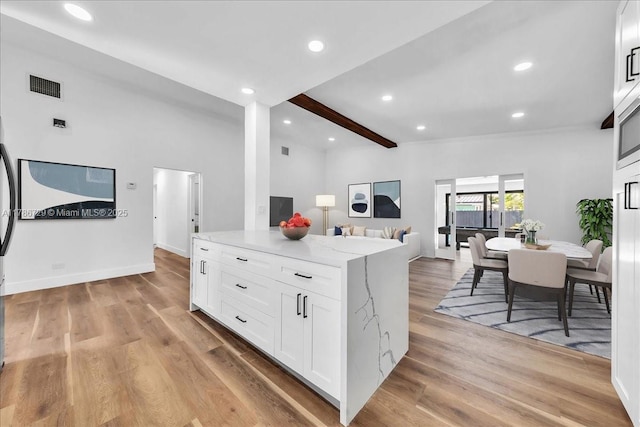 15020 NE 7th Ave, Miami, FL 33161 - kitchen with white cabinets, open floor plan, visible vents, beamed ceiling, and light stone counters