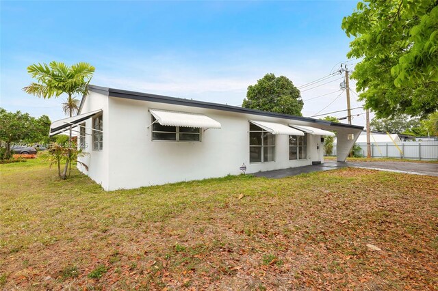 1920 N 66th Ave, Hollywood, FL 33024 - back of property featuring a lawn, fence, and stucco siding