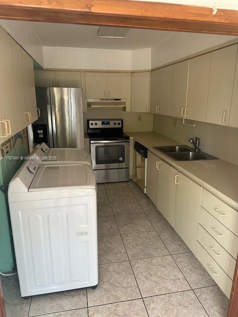 kitchen with stainless steel appliances, a sink, washer and clothes dryer, light tile patterned flooring, and under cabinet range hood