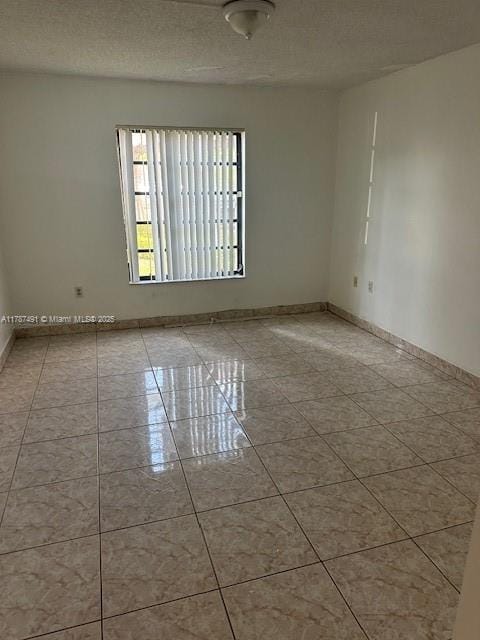 empty room featuring a textured ceiling and baseboards