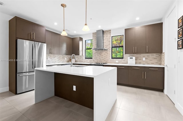 kitchen with light countertops, dark brown cabinets, wall chimney exhaust hood, and stainless steel appliances