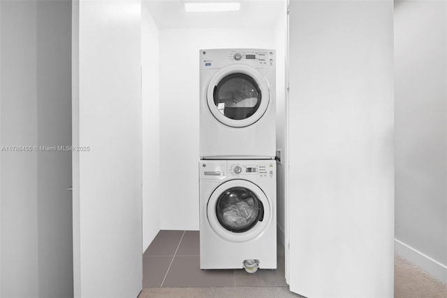 clothes washing area with tile patterned flooring, stacked washer / dryer, and laundry area