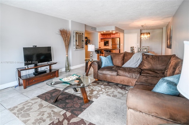 living room with tile patterned floors, a textured ceiling, baseboards, visible vents, and an inviting chandelier