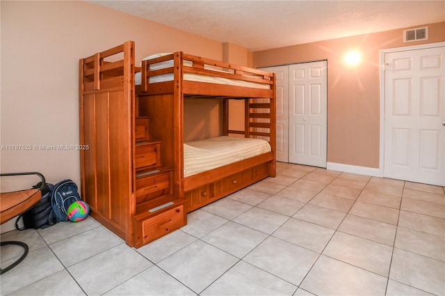 unfurnished bedroom featuring a closet, visible vents, and light tile patterned floors