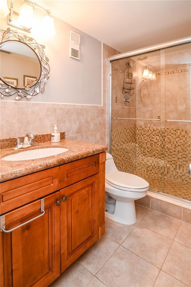 bathroom with toilet, a stall shower, tile patterned floors, and tile walls