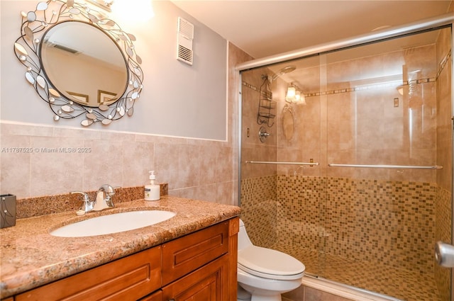 bathroom featuring a shower stall, visible vents, toilet, and tile walls