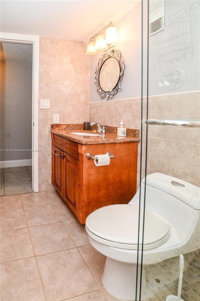 bathroom featuring tile patterned floors, toilet, tile walls, visible vents, and vanity