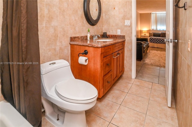 bathroom with ensuite bathroom, vanity, tile walls, toilet, and tile patterned flooring