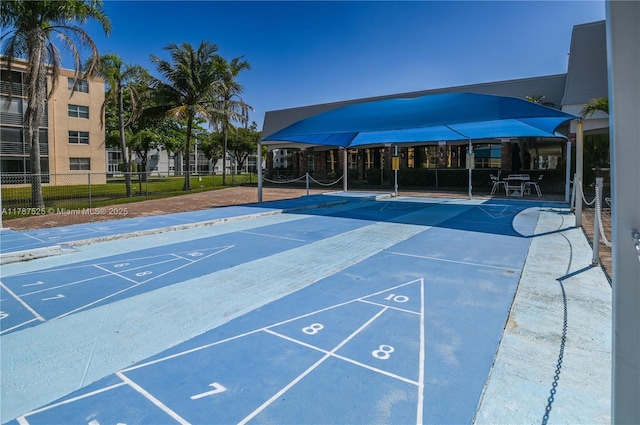 view of home's community featuring fence and shuffleboard