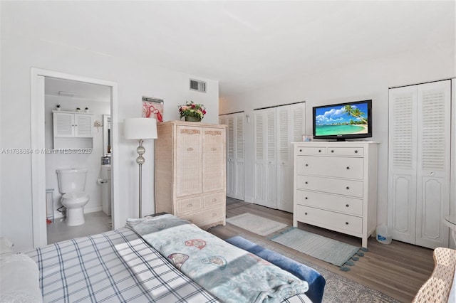 bedroom featuring wood finished floors, multiple closets, visible vents, and ensuite bathroom