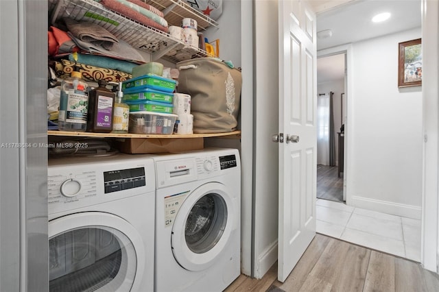 laundry room featuring washing machine and clothes dryer, wood finished floors, laundry area, and baseboards