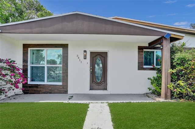 3411 SW 36th St, West Park, FL 33023 - view of exterior entry featuring stucco siding and a lawn