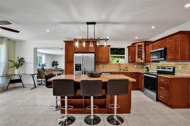 3411 SW 36th St, West Park, FL 33023 - kitchen featuring appliances with stainless steel finishes, decorative backsplash, a center island, light stone counters, and recessed lighting