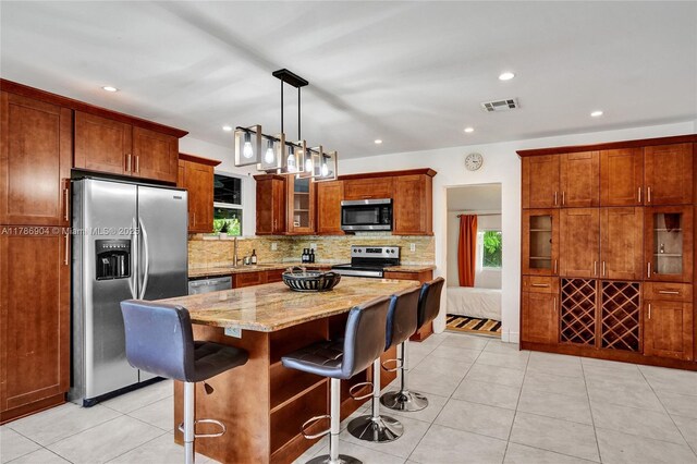 3411 SW 36th St, West Park, FL 33023 - kitchen with stainless steel appliances, tasteful backsplash, light stone countertops, a breakfast bar, and a kitchen island