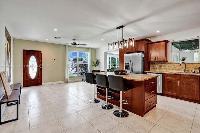 3411 SW 36th St, West Park, FL 33023 - kitchen featuring appliances with stainless steel finishes, light stone counters, a center island, backsplash, and a kitchen breakfast bar