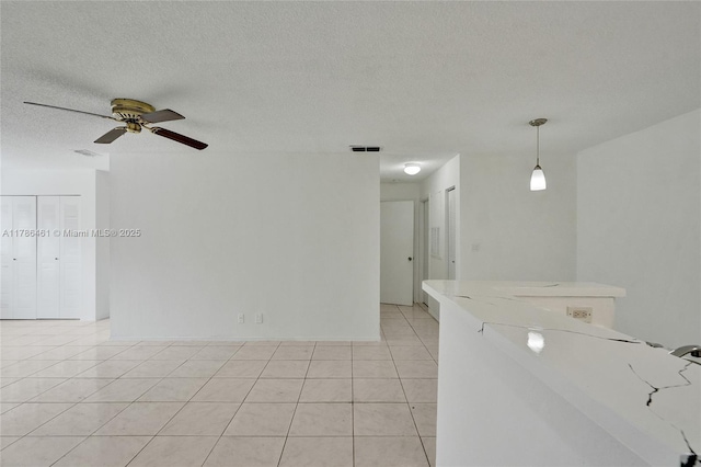 spare room featuring visible vents, a ceiling fan, a textured ceiling, and light tile patterned flooring