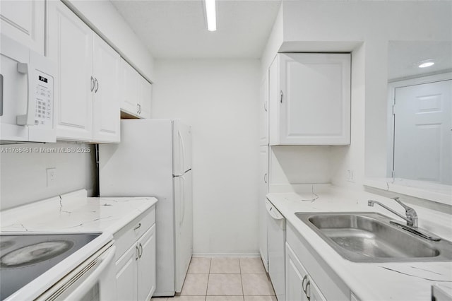 kitchen featuring a sink, light tile patterned flooring, white appliances, baseboards, and white cabinets
