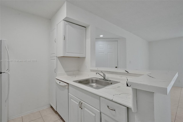 kitchen with a sink, light tile patterned floors, a peninsula, white appliances, and white cabinets
