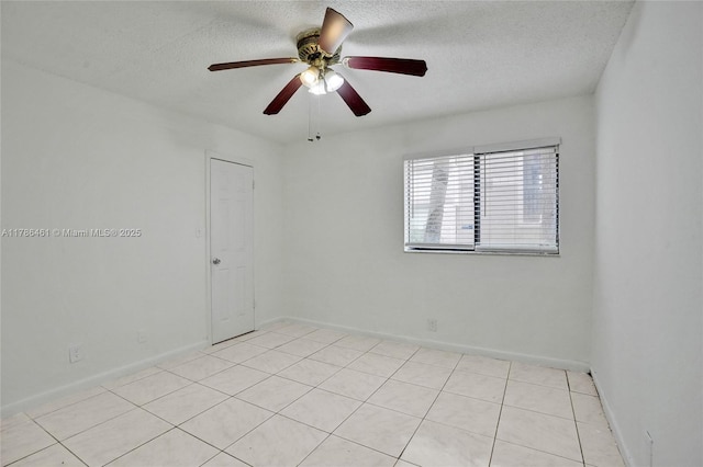 spare room with light tile patterned floors, a textured ceiling, a ceiling fan, and baseboards