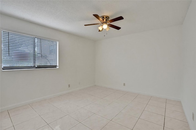 unfurnished room with light tile patterned floors, a ceiling fan, a textured ceiling, and baseboards