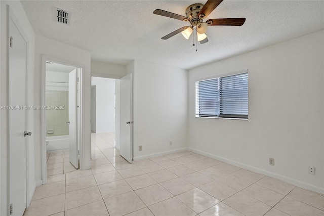 unfurnished bedroom featuring light tile patterned floors, visible vents, baseboards, and a textured ceiling