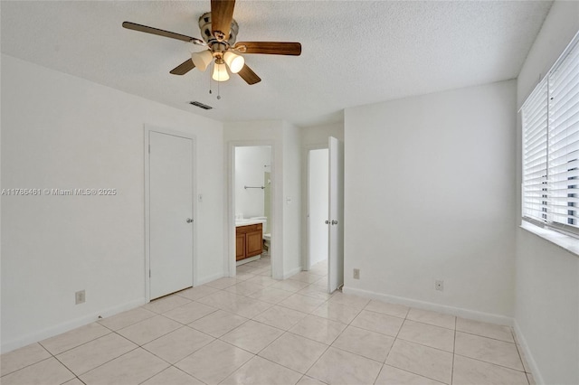spare room featuring baseboards, visible vents, a ceiling fan, a textured ceiling, and light tile patterned flooring