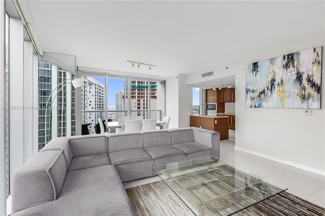 living room with visible vents, a city view, track lighting, and baseboards
