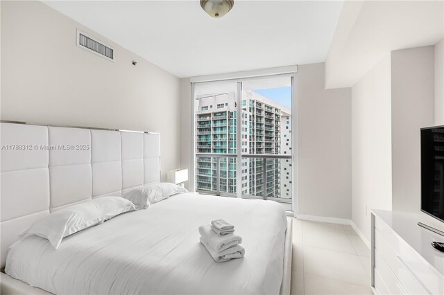 bedroom with expansive windows, baseboards, light tile patterned flooring, and visible vents