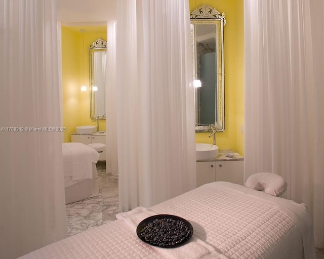 bedroom with ensuite bath, marble finish floor, and a sink