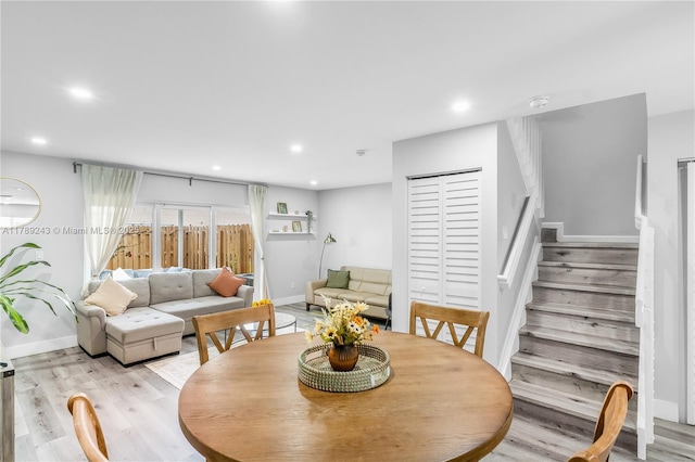 dining area featuring light wood-style flooring, baseboards, recessed lighting, and stairs