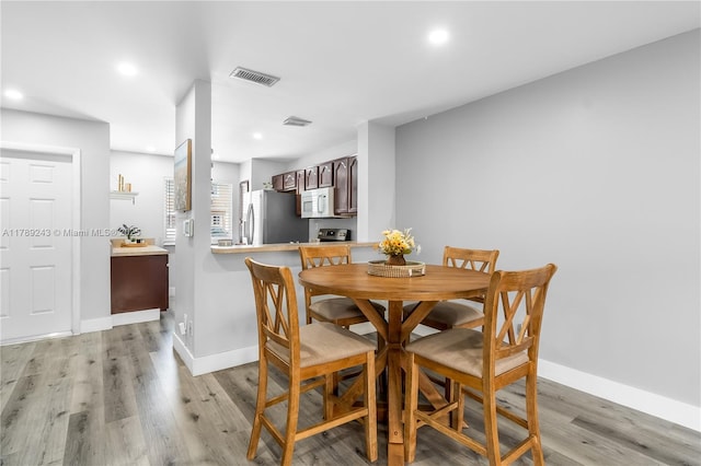 dining area with baseboards, light wood finished floors, visible vents, and recessed lighting