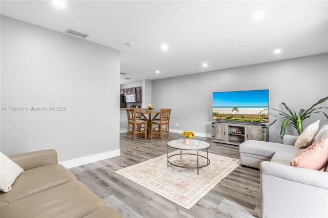 living room with baseboards, visible vents, and recessed lighting