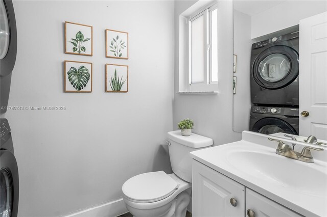 half bathroom with stacked washer and dryer, vanity, and toilet