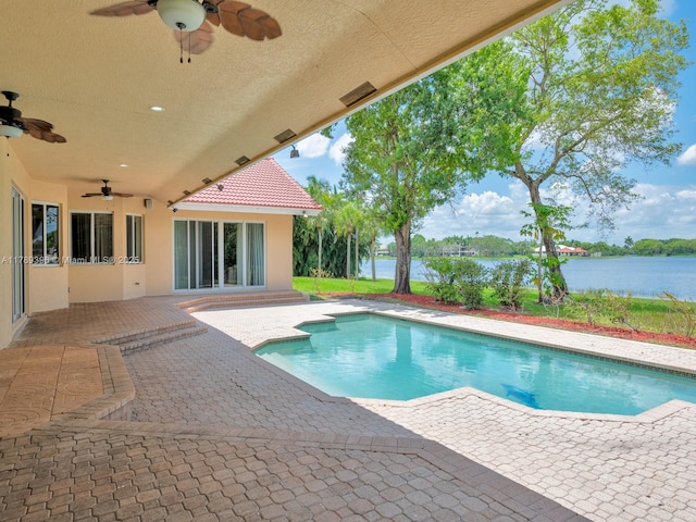 outdoor pool with a ceiling fan, a water view, and a patio area