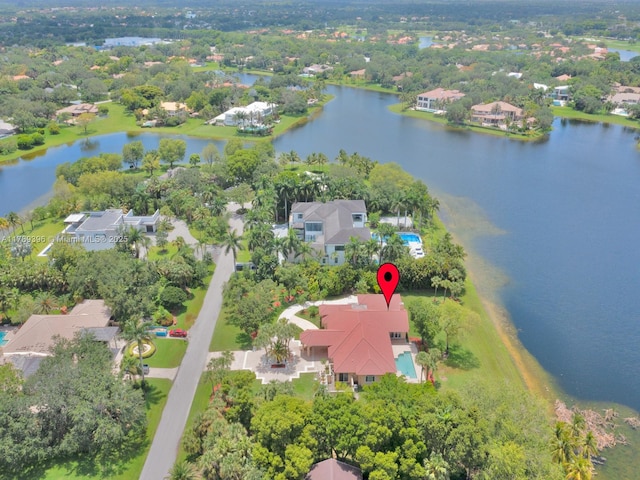 view of property location with nearby suburban area, a nearby body of water, and a tree filled landscape